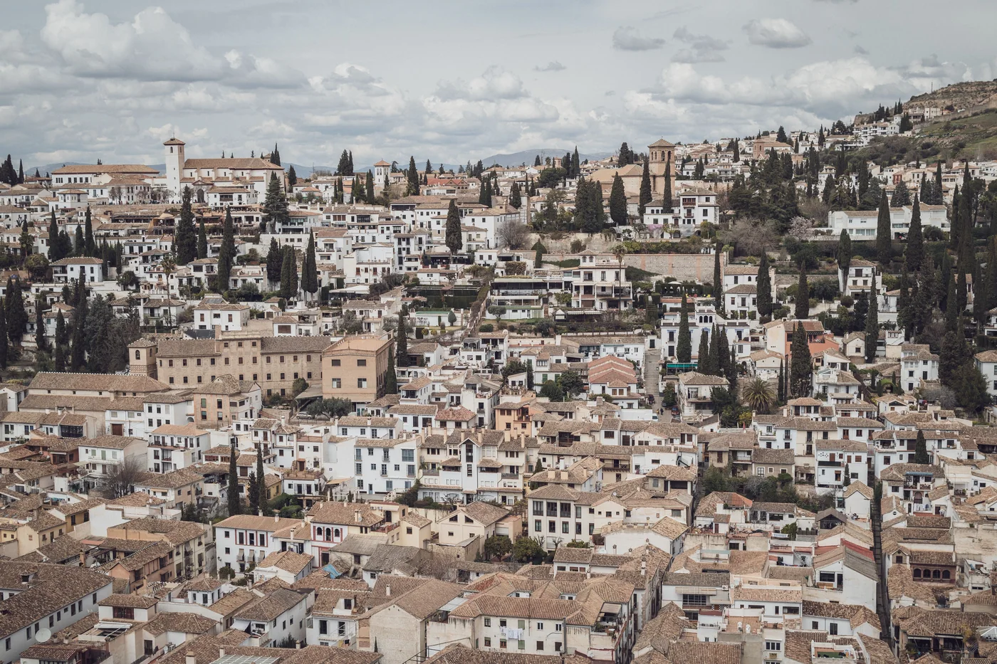 Whitewashed cave houses on the Sacromonte hillside with the Alhambra beyond
